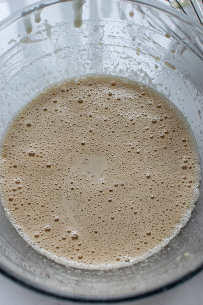 Oil, egg, sugar and coffee whipped with a wire whisk in a glass mixing bowl.