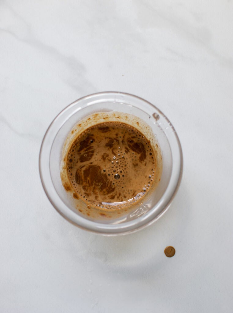 A bit of water added to espresso powder in a clear plastic cup.