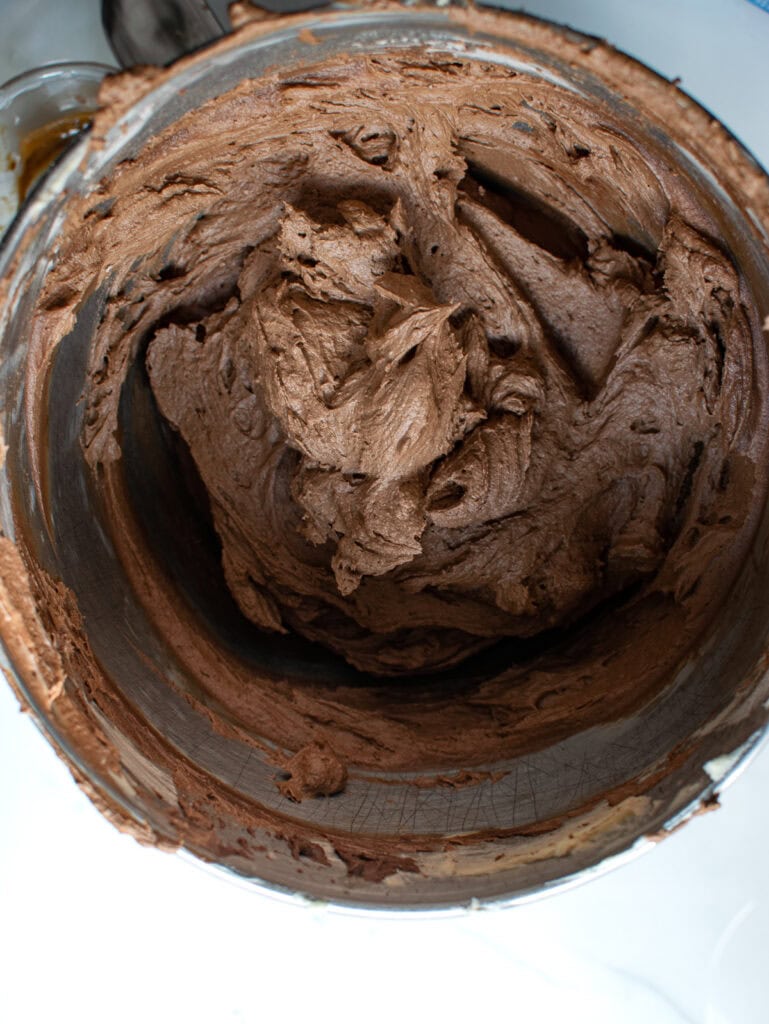 Chocolate coffee buttercream frosting in the bowl of a stand mixer.