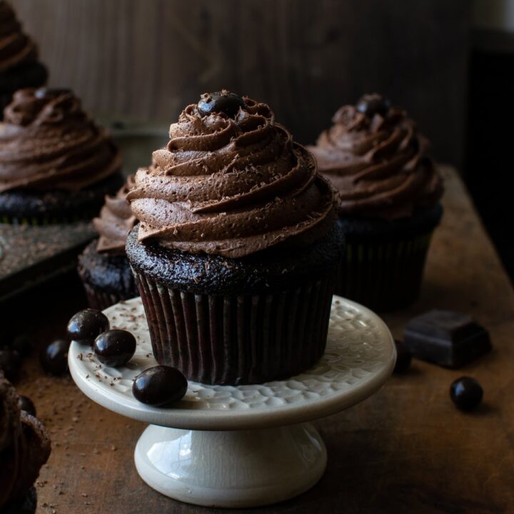 A close up photo of a chocolate coffee cupcake on a cupcake stand.