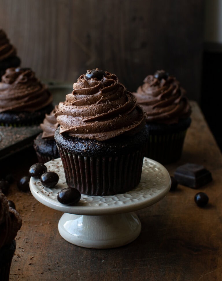 A close up photo of a chocolate coffee cupcake on a cupcake stand.