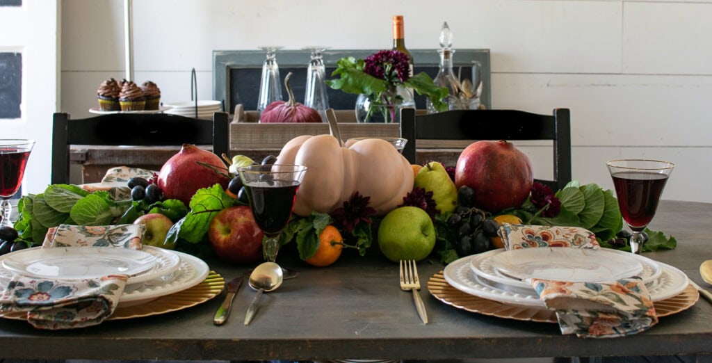 A centrepiece on a Thanksgiving Harvest tablescape with fresh fruits and pumpkin.