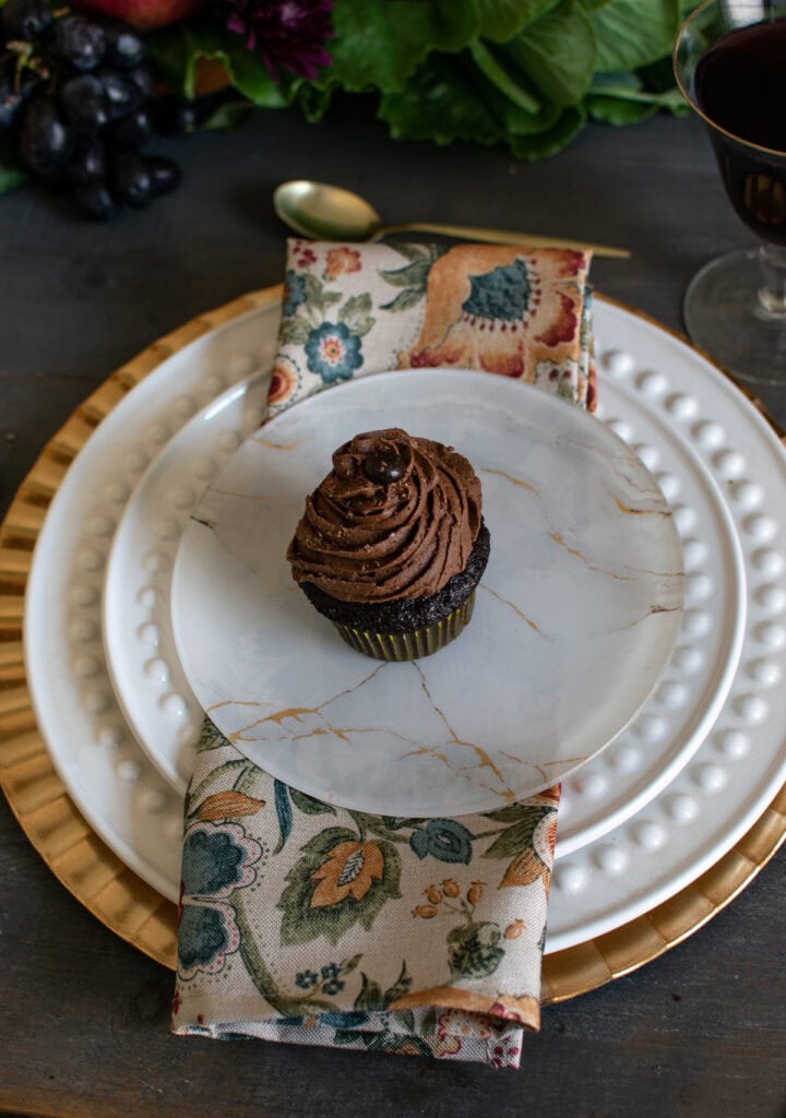 A Thanksgiving Harvest tablescape with a chocolate cupcake on top of gold marbled dessert plates.