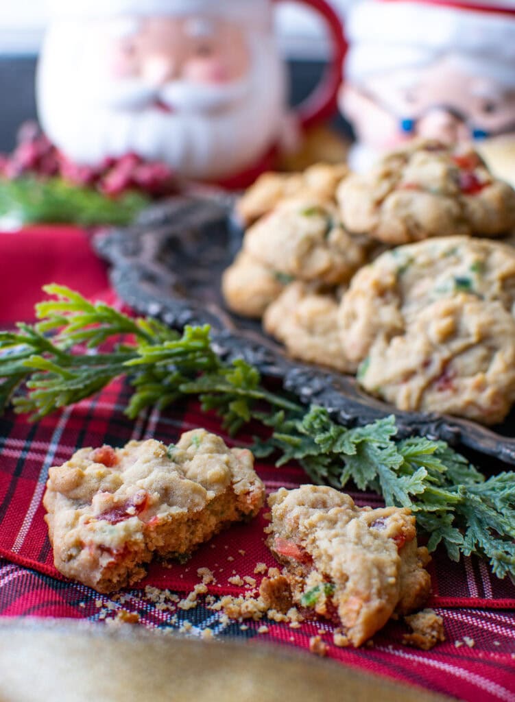 A cherry drop cookie cut in half, with a plate full of cookies in the background.