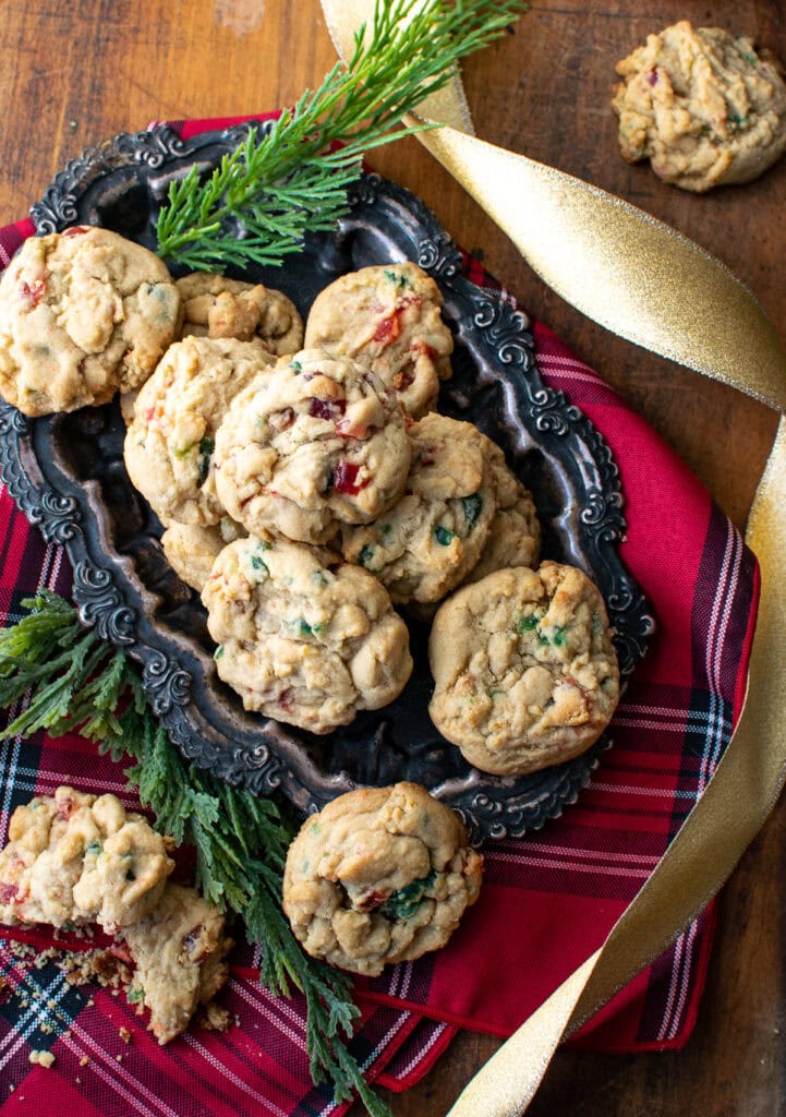 An overhead view of candied cherry drop cookies on a tarnished silver tray.