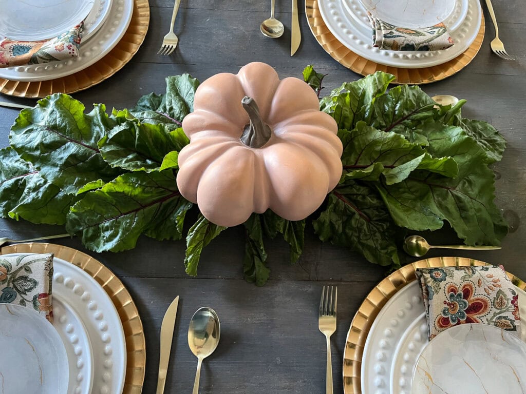 An over head view of beet greens laid out on a table as the base for a Thanksgiving harvest table.