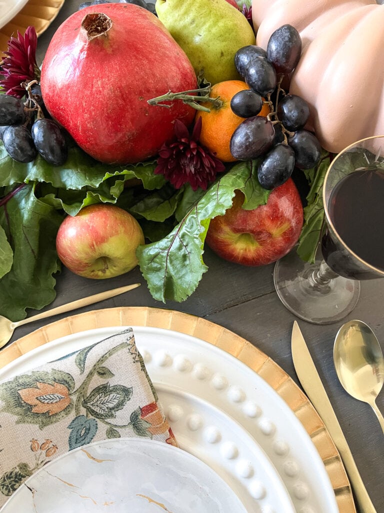 An close up overhead view of a fresh fruit centrepiece and a plate stack for Thanksgiving.