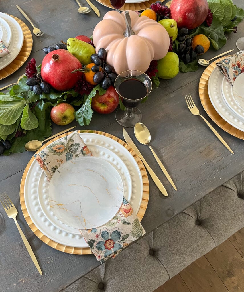 Overhead view of a tablescape set for Thanksgiving with a fresh fruit centrepiece running down the centre of the table.