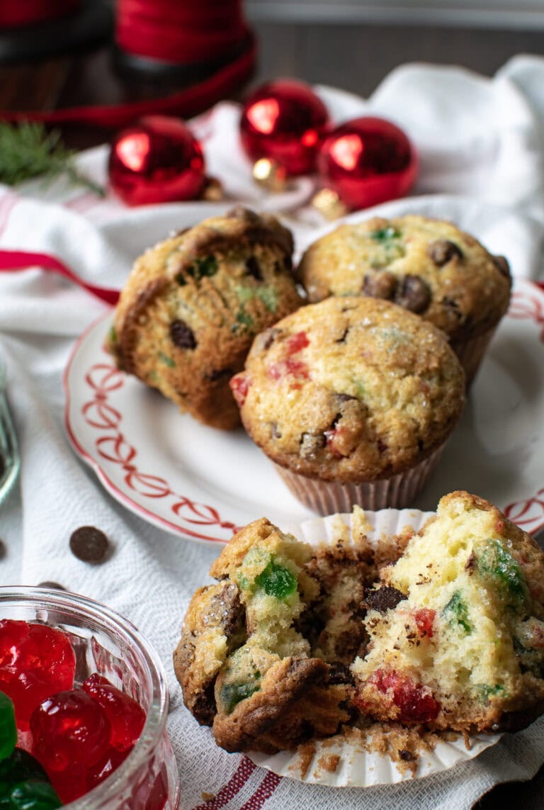 3 cherry chocolate chip muffins on a plate, with one in the foreground that has been cut in half.