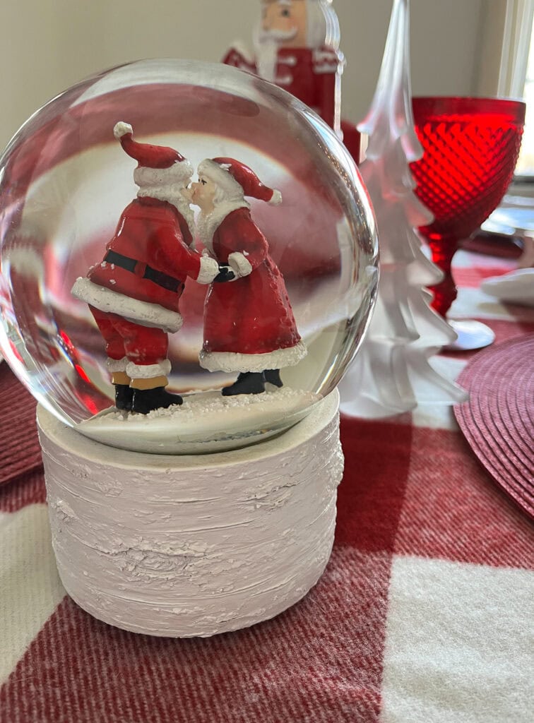 A snow globe music box with a kissing Santa and Mrs. Claus inside.