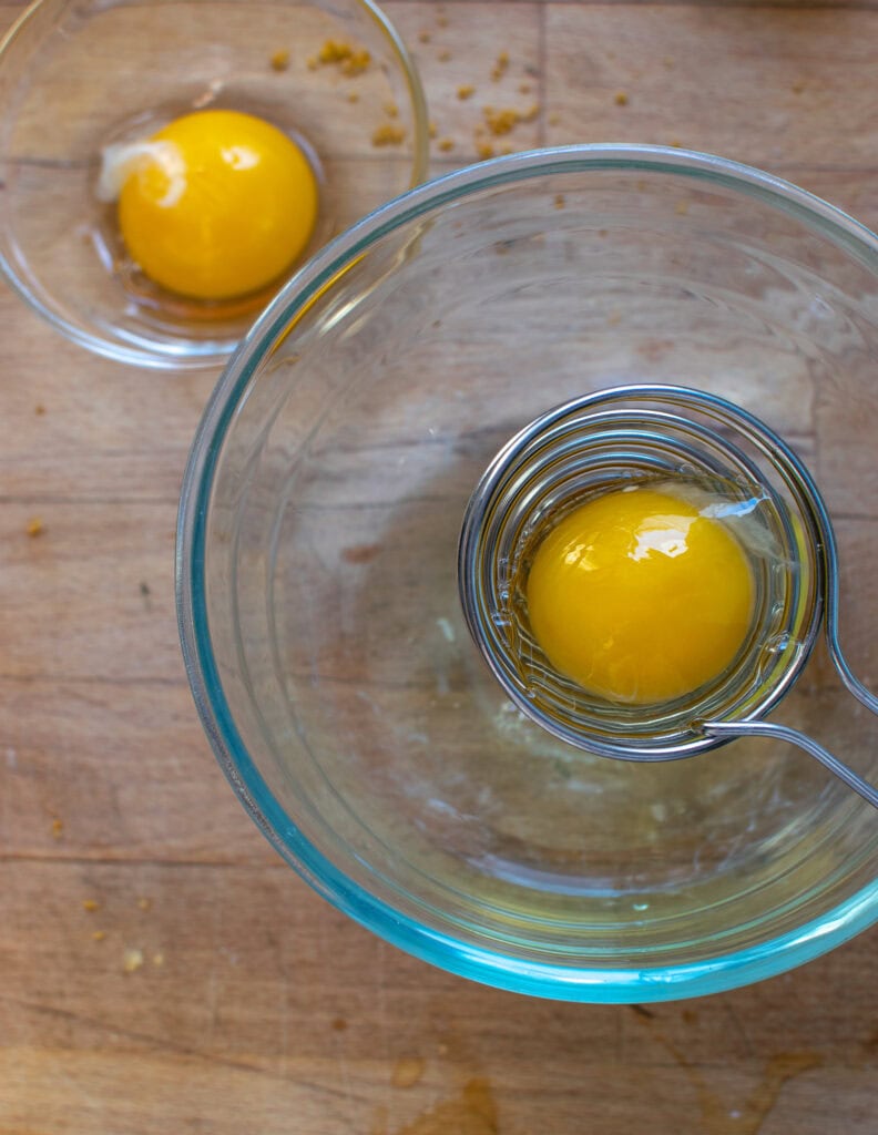 Eggs being separated into a glass bowl.