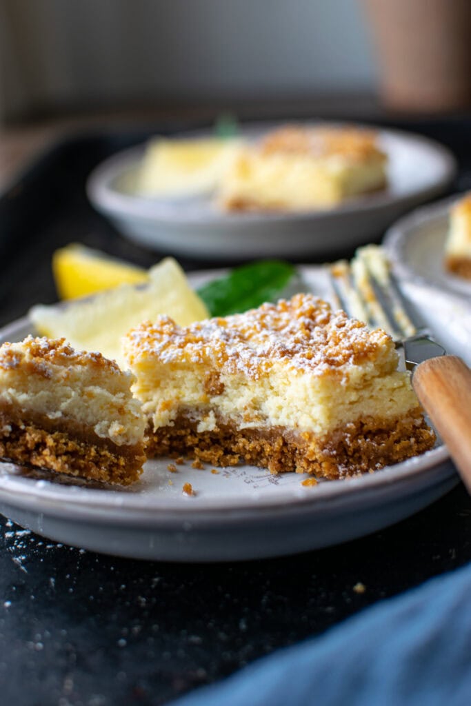 A close up of a fluffy lemon square with a graham cracker crust and topping.