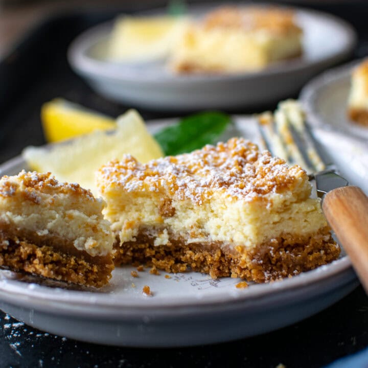 A close up of a fluffy lemon square with a graham cracker crust and topping.