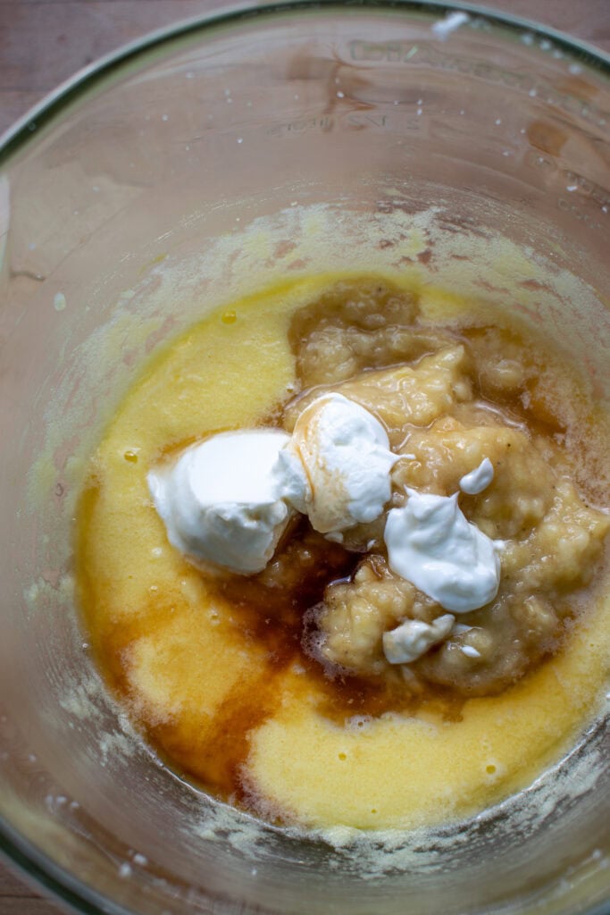 Mashed banana, yogurt, rum and vanilla added to egg and butter mixture for banana bread recipe.