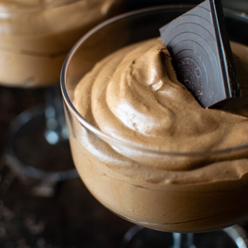 Dark Chocolate Mousse in a cocktail glass with a square of dark chocolate for a garnish.