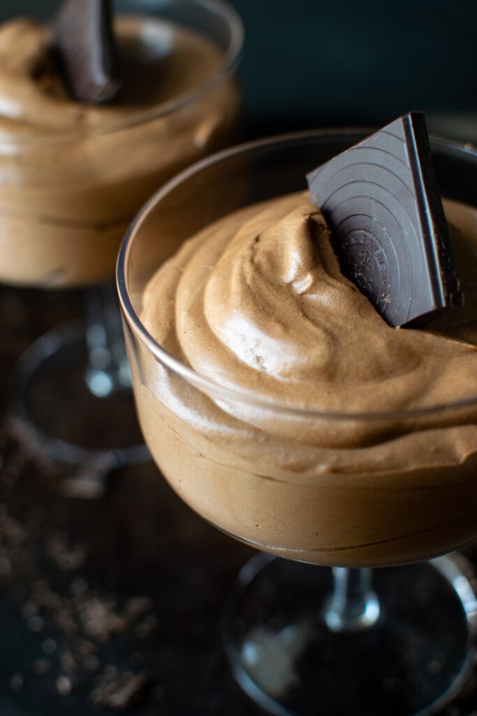 Dark Chocolate Mousse in a cocktail glass with a square of dark chocolate for a garnish.