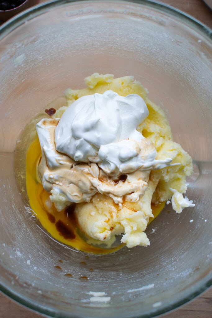 Eggs, sour cream, and vanilla added to creamed butter and sugar mixture to make a coffee cake.