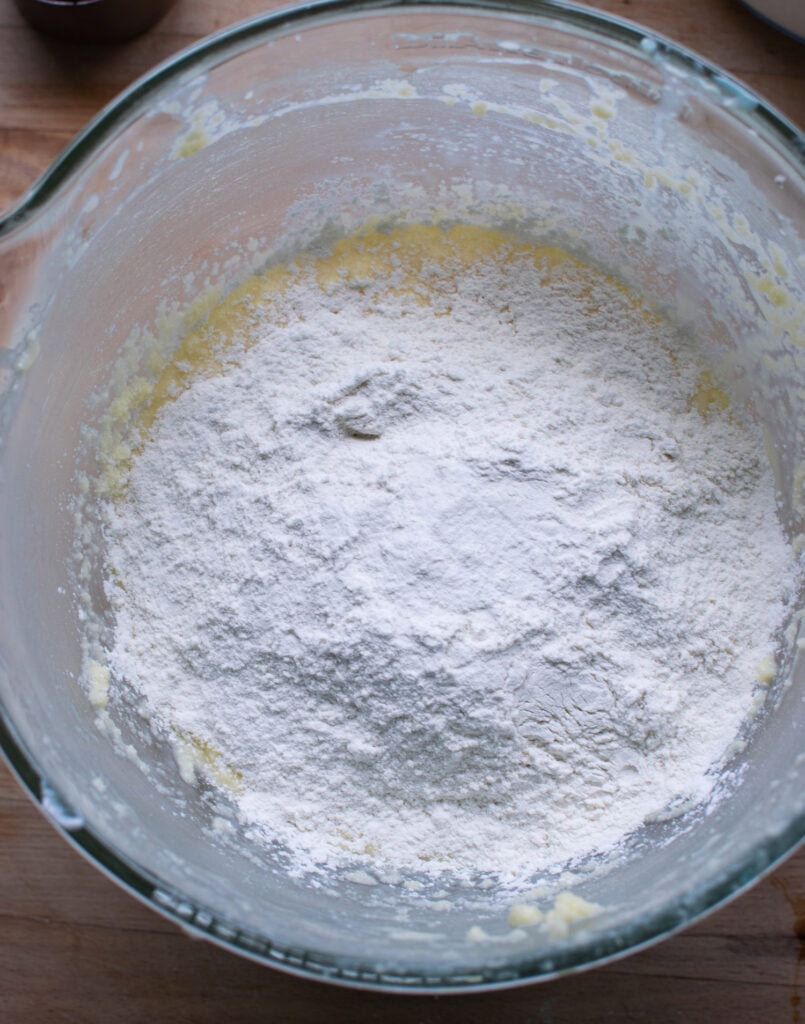 Flour added to a mixing bowl with wet ingredients to make a blueberry sour cream coffee cake.