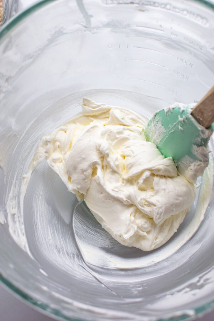 Softened cream cheese combined with fresh whipped cream in a glass bowl.