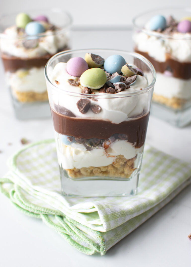 3 chocolate parfaits in dessert cups, with on sitting on a green gingham napkin.