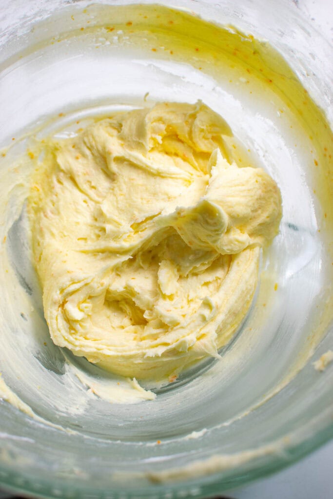 Orange buttercream frosting in the bowl of electric mixer.