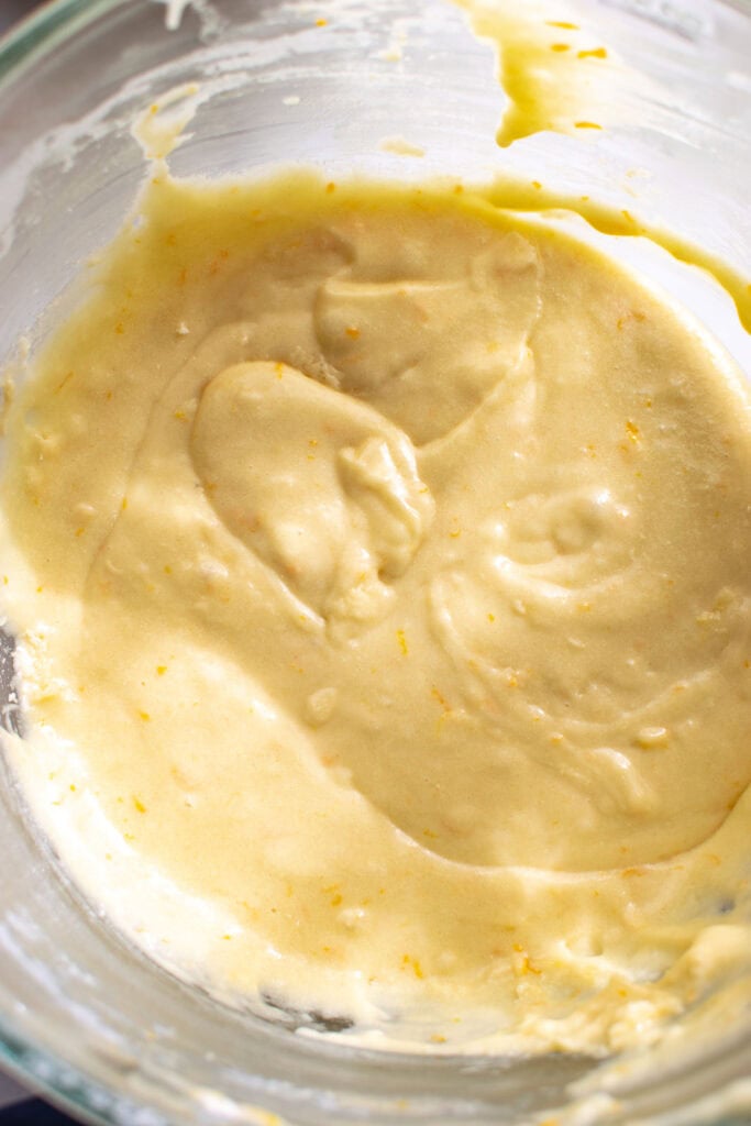 Batter in a glass mixing bowl to make an orange cake.